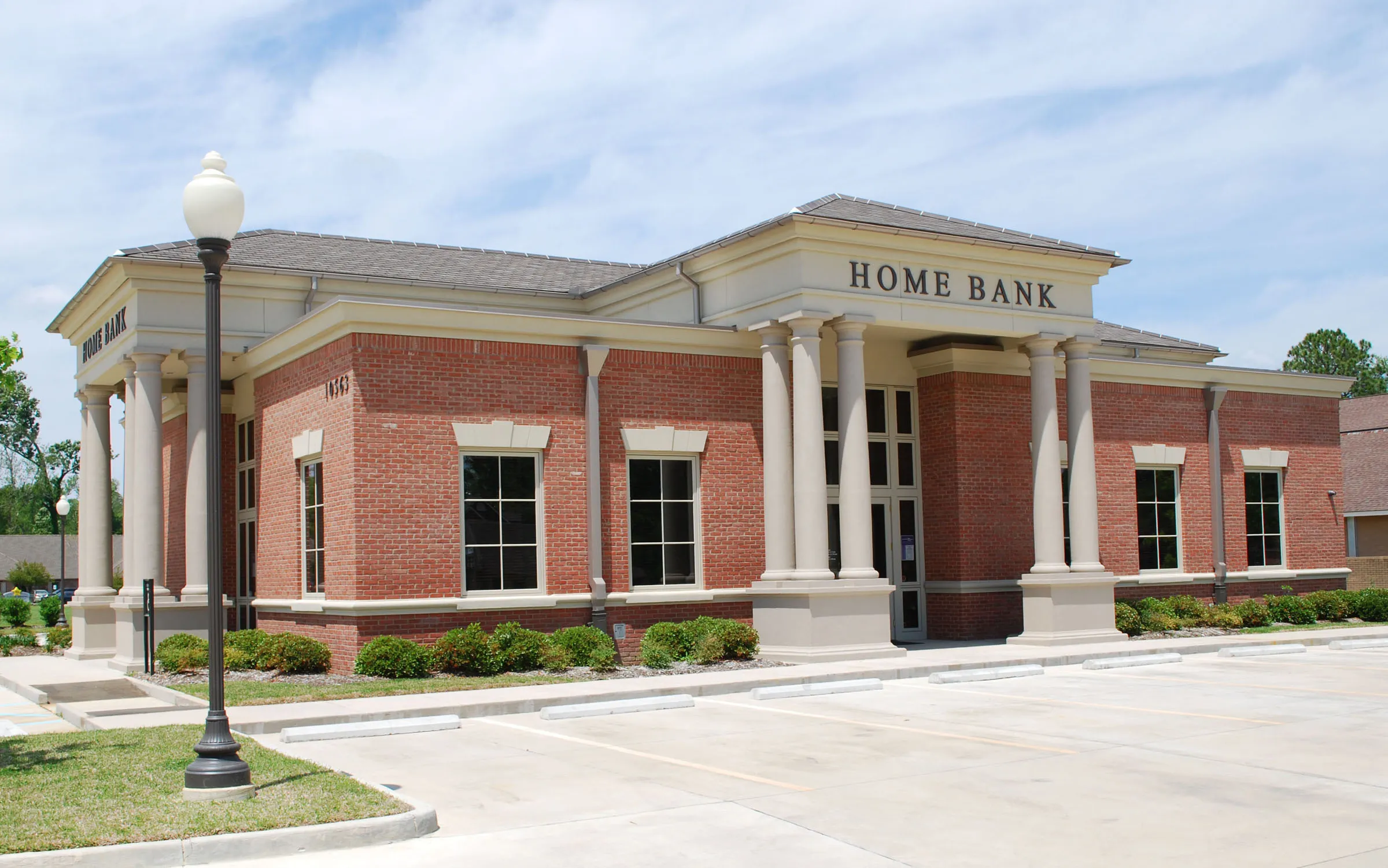 A classical red-brick Home Bank branch with columns, built by C.M. Miciotto & Son in Louisiana.